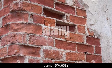 Vista da vicino sulle vecchie pareti in mattoni. Un frammento esposto delle mura medievali del castello dopo i lavori di conservazione. Un elemento di design esterno dell'histori Foto Stock