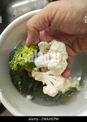 immergere piccoli pezzi di cavolfiore bianco e verde nel contenitore. Foto Stock