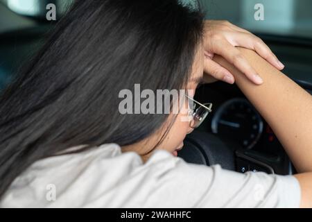 Le giovani donne asiatiche si sentono sonnolente durante la guida Foto Stock