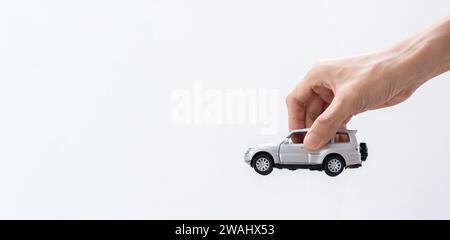 Mano che regge un'auto giocattolo isolata su sfondo gradiente. Dopo alcune modifiche. Foto Stock