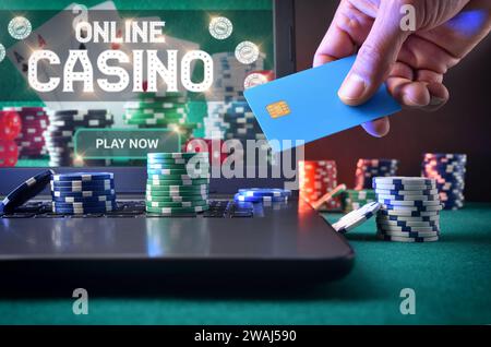 Giocatore di casinò che accede a una carta di pagamento per fare scommesse virtuali utilizzando un computer portatile. Vista frontale. Foto Stock