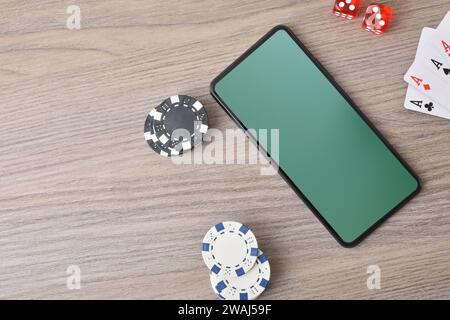 Concetto di gioco da casinò virtuale con smartphone su un tavolo di legno e oggetti intorno. Vista dall'alto. Foto Stock