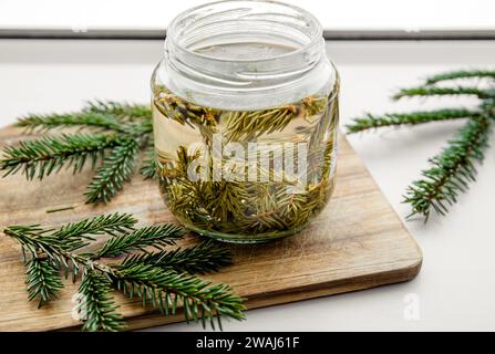 Preparazione dello sciroppo di aghi picea di abete rosso fresco. Vasetti di vetro con aghi infusi d'acqua nella cucina domestica. Foto Stock