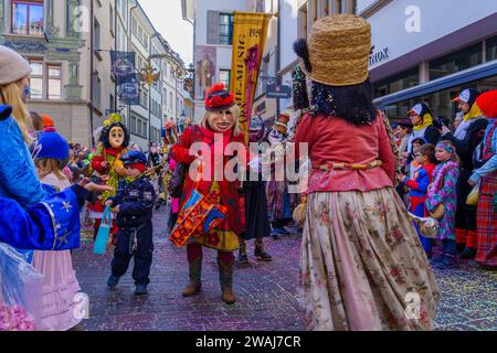 Lucerna, Svizzera - 21 febbraio 2023: Gruppo di partecipanti in costume marzo per le strade, e folla, parte della parata dei bambini del Fasnac Foto Stock