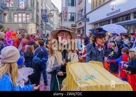 Lucerna, Svizzera - 21 febbraio 2023: Gruppo di partecipanti in costume marzo per le strade, e folla, parte della parata dei bambini del Fasnac Foto Stock