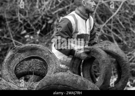 Lavoratore che pulisce pneumatici e letame scaricati dopo la protesta degli agricoltori, Quai Eugène Cavaignac, Cahors, dipartimento Lot, Francia Foto Stock