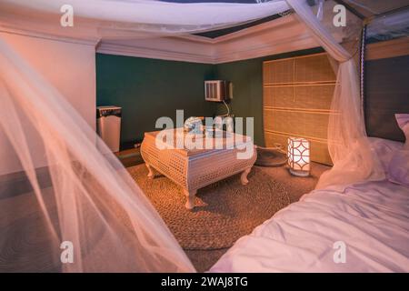 Camera da letto con luce soffusa e tavolo con bollitore Foto Stock