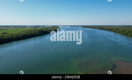 Questa vista aerea cattura un paesaggio mozzafiato con un lago tranquillo e una foresta lussureggiante sullo sfondo Foto Stock
