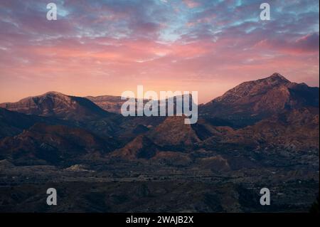 Le maestose vette di Alicante si crogiolano nel caldo bagliore del crepuscolo sotto un vivace cielo al tramonto Foto Stock