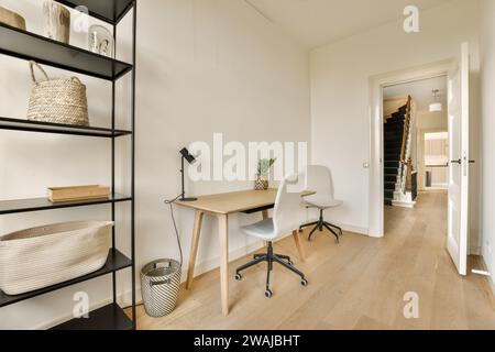 Lampada sulla scrivania dello spazioso ufficio domestico di una casa moderna con scala vista attraverso la porta aperta Foto Stock