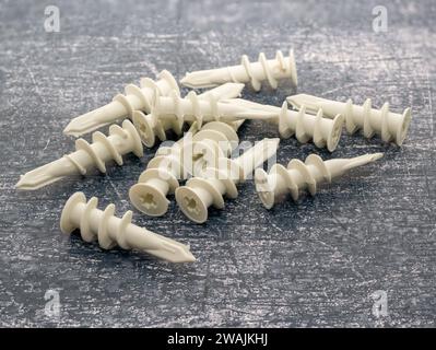 Tappi di ancoraggio per pareti autoforanti bianchi isolati su uno sfondo di cemento Foto Stock