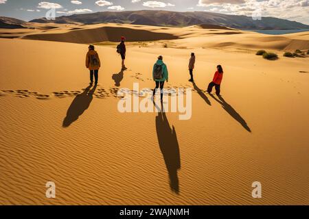 Diversi gruppi di turisti si trovano alle dune al tramonto. Persone e silhouette contro dune sabbiose Foto Stock