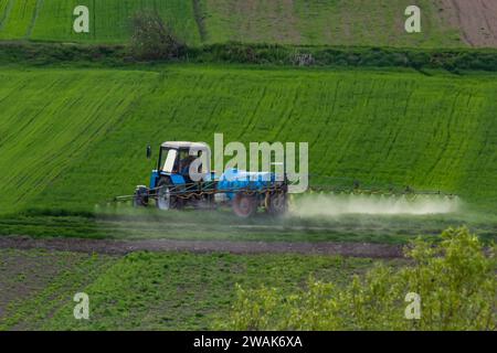 Vista aerea del trattore che spruzza il prodotto in campi verdi con pesticidi. Foto Stock