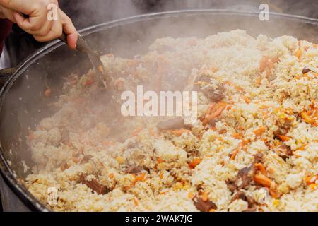 Cucina il tradizionale pilaf uzbeko nel calderone al festival del cibo di strada Foto Stock