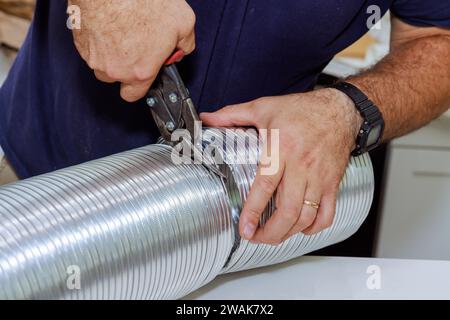 Uomo che taglia tubo corrugato flessibile in alluminio per il condotto dell'aria di sfiato Foto Stock