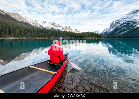 Vista posteriore di un turista maschile in canoa invernale con pagaia a Spirit Island sul lago Maligne presso il parco nazionale di Jasper, Alberta, Canada Foto Stock