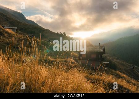 L'alba splende su un vecchio cottage in legno sulla collina tra le Alpi svizzere nel villaggio di montagna Findeln a Zermatt, Svizzera Foto Stock
