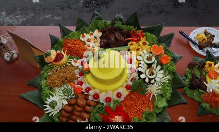 Riso a forma di cono o chiamato Nasi Tumpeng Un piatto di riso indonesiano festoso con contorni Foto Stock