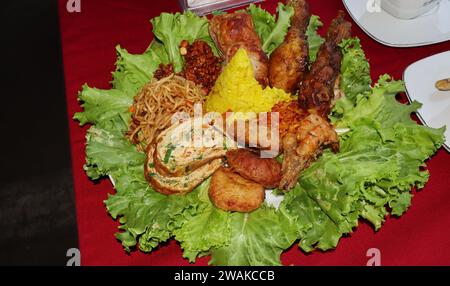 Riso a forma di cono o chiamato Nasi Tumpeng Un piatto di riso indonesiano festoso con contorni Foto Stock