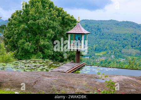 Una piccola statua di Buddha situata nel mezzo di uno splendido paesaggio collinare a kandy, sri lanka Foto Stock