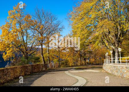 Sentiero con lanterne e muro di pietra tra alberi autunnali Foto Stock
