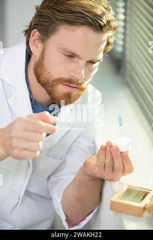 scienziato chimico maschio collocare il campione di liquido sul vetrino del microscopio Foto Stock