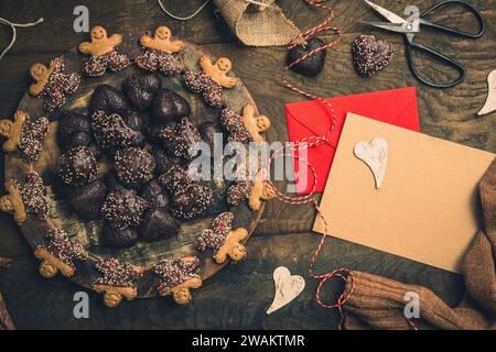 Scena per regali all'Avvento con biscotti, nastro regalo e biglietto per testo su fondo in legno scuro, idea natalizia. spazio di copia, vista dall'alto Foto Stock