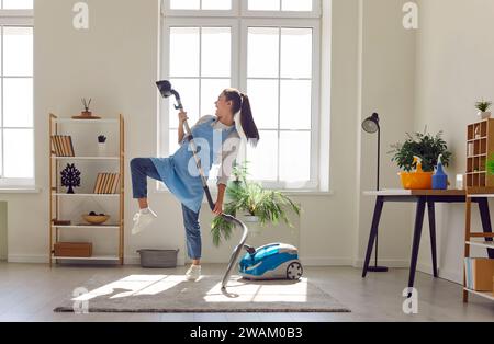 Donna che balla mentre aspira nel soggiorno Foto Stock