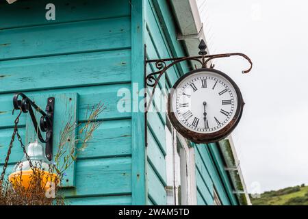 Vecchio orologio in metallo arrugginito appeso alla parete turchese di una casa di legno Foto Stock