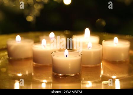 Vista ravvicinata di diverse candele a lume di tè in fiamme con messa a fuoco selettiva Foto Stock