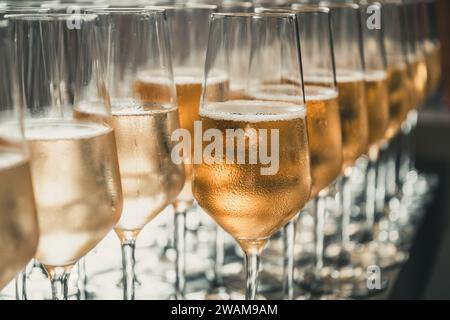 Una fila di bicchieri pieni di champagne sono pronti per essere serviti Foto Stock