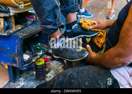 Un uomo brasiliano che lucida le scarpe di un altro uomo a Belo Horizonte, Minas Gerais, Brasile. Foto Stock