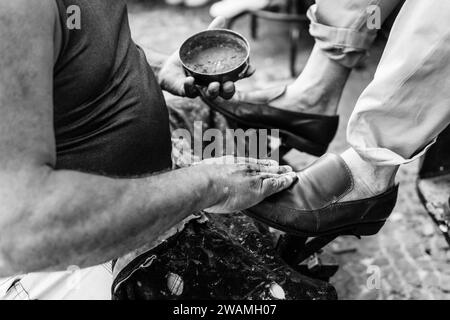 Fotografia in bianco e nero di un uomo brasiliano che lucida le scarpe di un altro uomo a Belo Horizonte, Minas Gerais, Brasile. Foto Stock