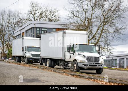 Semi-carri da lavoro standard per impieghi medi con cabina corta bianca con rimorchi scatolati per consegne locali ed esigenze di piccole imprese in magazzino Foto Stock