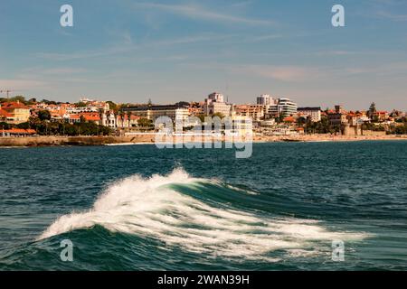 Onde oceaniche e la città di Estoril Portogallo sullo sfondo Foto Stock