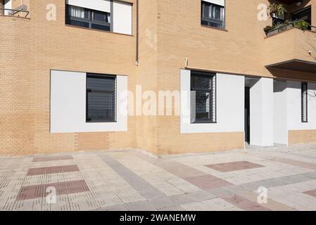 Porte di accesso alle case in stile loft al piano terra di un edificio con mattoni di colore chiaro e finestre con barre di sicurezza Foto Stock