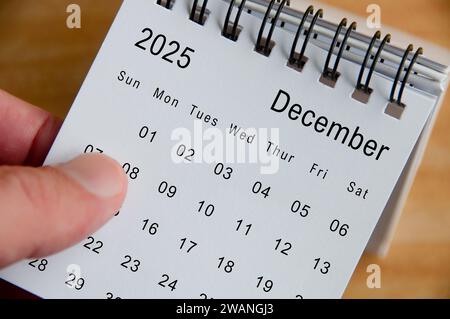 Vista ravvicinata del calendario di dicembre 2025 su sfondo di una scrivania in legno. Concetto di calendario. Foto Stock