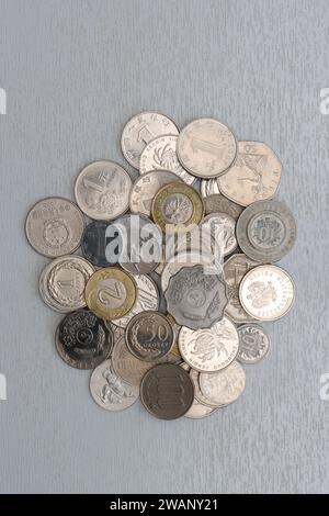 Foto verticale di una varietà di monete metalliche su sfondo chiaro, vista dall'alto. Foto Stock