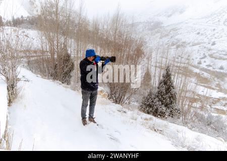 un fotografo che scatta foto in inverno durante le nevicate Foto Stock