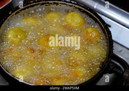 friggere palle di patate precedentemente bollite in acqua calda, patate fritte in olio alimentare bollente, messa a fuoco selettiva Foto Stock