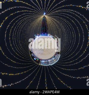 Anno nuovo piccolo pianeta con albero di Natale. Antenna sferica vista notturna panoramica a 360° sulla piazza festosa con illuminazione sotto forma di tenda Foto Stock