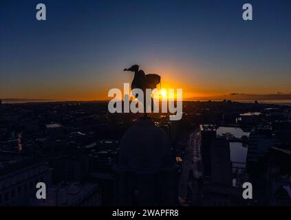 Il sole sorge dietro uno degli uccelli del fegato, seduto in cima al Royal Liver Building a Liverpool. Quasi 250 avvertimenti sulle inondazioni rimangono in vigore in Inghilterra e Galles, poiché le condizioni continuano a causare problemi di viaggio in vaste parti del paese. Data immagine: Sabato 6 gennaio 2024. Foto Stock