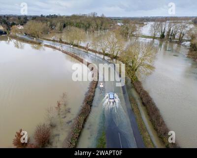 Grantchester, Cambridge, 6 gennaio 2024. Il fiume Cam ha fatto irruzione sulle sue sponde che inondano la strada attraverso il villaggio, i campi circostanti e i famosi prati di Grantchester dopo settimane di tempo umido. Le auto possono ancora passare con cura. Periodi prolungati di forti piogge hanno causato inondazioni in gran parte del Regno Unito quest'inverno. Crediti: Julian Eales/Alamy Live News Foto Stock