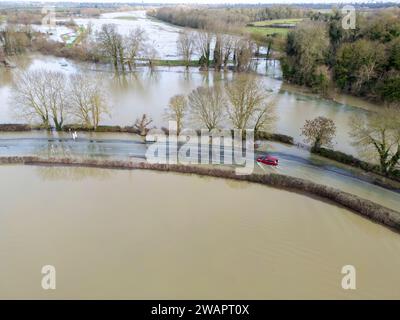 Grantchester, Cambridge, 6 gennaio 2024. Il fiume Cam ha fatto irruzione sulle sue sponde che inondano la strada attraverso il villaggio, i campi circostanti e i famosi prati di Grantchester dopo settimane di tempo umido. Le auto possono ancora passare con cura. Periodi prolungati di forti piogge hanno causato inondazioni in gran parte del Regno Unito quest'inverno. Crediti: Julian Eales/Alamy Live News Foto Stock