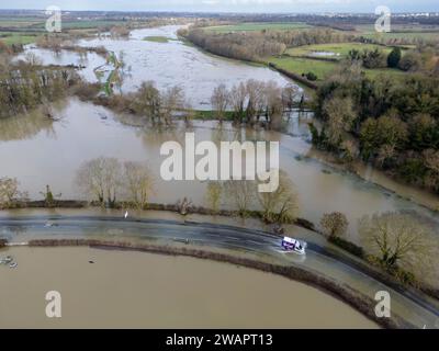 Grantchester, Cambridge, 6 gennaio 2024. Il fiume Cam ha fatto irruzione sulle sue sponde che inondano la strada attraverso il villaggio, i campi circostanti e i famosi prati di Grantchester dopo settimane di tempo umido. Le auto possono ancora passare con cura. Periodi prolungati di forti piogge hanno causato inondazioni in gran parte del Regno Unito quest'inverno. Crediti: Julian Eales/Alamy Live News Foto Stock