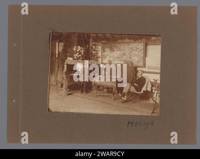 Ragazza al pianoforte, uomo seduto in sedia interna, ca. 1916, 1916 Fotografia ragazza che suona al pianoforte a sinistra nella foto, uomo con barba nella poltrona a destra. Grande dipinto sullo sfondo con motivi vegetali. Dallo stesso album: RP-F-00-6024. supporto fotografico. stampa in argento gelatina di cartone Foto Stock