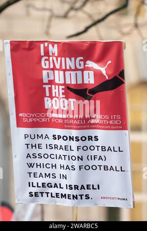 Manchester, Regno Unito. 6 gennaio 2024. Firmi una critica al sostegno di Puma alla politica israeliana. I manifestanti a Manchester Regno Unito contro la guerra a Gaza. Protesta palestinese nel centro di Manchester. REGNO UNITO. Più di duemila manifestanti si sono riuniti in Piazza San Pietro per chiedere un cessate il fuoco. Poi marciarono attraverso il centro della città. La polizia ha sorvegliato i punti vendita che i manifestanti hanno detto avere legami con Israele, tra cui Barclays Bank e Starbucks Coffee. I manifestanti sventolavano bandiere e portavano cartelli con slogan contro la guerra. Manchester Regno Unito. Foto: Garyroberts/worldwidefeatures.com credito: GaryRobertsphotography/Alamy Live N Foto Stock