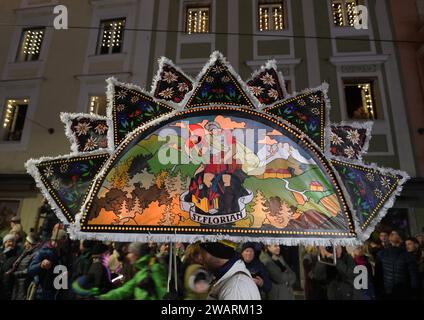 Dreikönigsingen und Glöcklerlauf am Rathausplatz in Gmunden, im oberösterreichischen Salzkammergut, AM 05.01.2024. Sowohl das Dreikönigssingen als auch der Glöcklerlauf sind alte, eingeprägte Brauchtumsveranstaltungen im Salzkammergut in Österreich. während des Glöcklerlaufs tragen junge Burschen prächtig geschmückte Laternenkappen mit meist lokalen Motiven am Kopf. Dabei wird durch laufen, springen und tanzen, mit an Gürteln der Weiß Gekleideten angebrachten Glocken, entsprechend Lärm gemacht und dazu gesungen Damit treiben die Glöckler in der letzten Rauhnacht der Saison, dem 5,1. eines jede Foto Stock