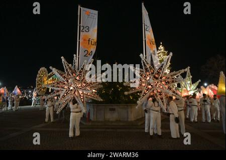 Dreikönigsingen und Glöcklerlauf am Rathausplatz in Gmunden, im oberösterreichischen Salzkammergut, AM 05.01.2024. Sowohl das Dreikönigssingen als auch der Glöcklerlauf sind alte, eingeprägte Brauchtumsveranstaltungen im Salzkammergut in Österreich. während des Glöcklerlaufs tragen junge Burschen prächtig geschmückte Laternenkappen mit meist lokalen Motiven am Kopf. Dabei wird durch laufen, springen und tanzen, mit an Gürteln der Weiß Gekleideten angebrachten Glocken, entsprechend Lärm gemacht und dazu gesungen Damit treiben die Glöckler in der letzten Rauhnacht der Saison, dem 5,1. eines jede Foto Stock