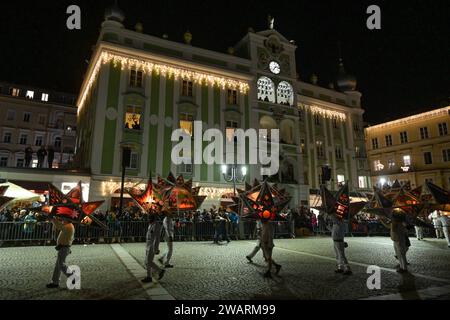 Dreikönigsingen und Glöcklerlauf am Rathausplatz in Gmunden, im oberösterreichischen Salzkammergut, AM 05.01.2024. Sowohl das Dreikönigssingen als auch der Glöcklerlauf sind alte, eingeprägte Brauchtumsveranstaltungen im Salzkammergut in Österreich. während des Glöcklerlaufs tragen junge Burschen prächtig geschmückte Laternenkappen mit meist lokalen Motiven am Kopf. Dabei wird durch laufen, springen und tanzen, mit an Gürteln der Weiß Gekleideten angebrachten Glocken, entsprechend Lärm gemacht und dazu gesungen Damit treiben die Glöckler in der letzten Rauhnacht der Saison, dem 5,1. eines jede Foto Stock